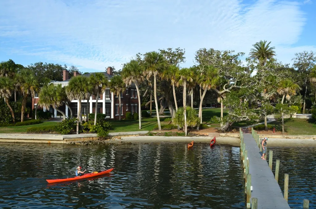 Kayaker passing Bay Preserve’s palm-lined waterfront and dock